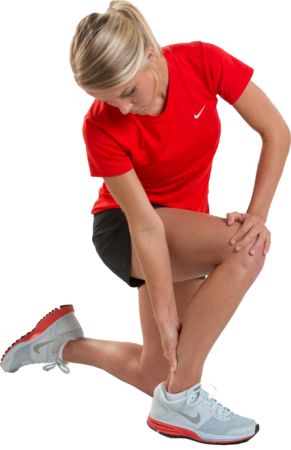 Woman in athletic wear kneels on one knee, holding her left ankle and stretching her leg. She wears a red shirt, black shorts, and white running shoes.